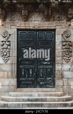 Portes doubles en bois vieilli ornées au fini vieilli et vieilli, situées dans une arche en pierre décorée de sculptures florales et de fruits complexes. E Banque D'Images