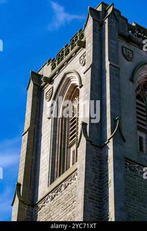 Une vue rapprochée d'une tour de pierre avec des détails architecturaux complexes, avec des fenêtres cintrées et des éléments décoratifs. Le ciel est clair et bleu, pr Banque D'Images