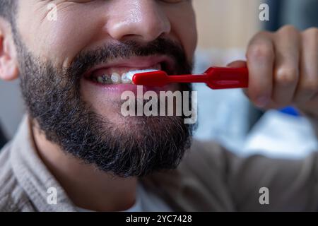 Homme caucasien dans la clinique dentaire brossant les dents et les appareils dentaires à l'aide de brosse à dents pour une routine quotidienne saine Banque D'Images