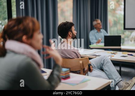 Les étudiants écoutent attentivement le professeur âgé en classe Banque D'Images