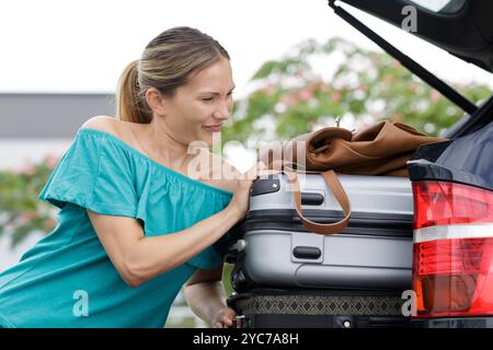 femme met un sac à bagages dans une voiture Banque D'Images