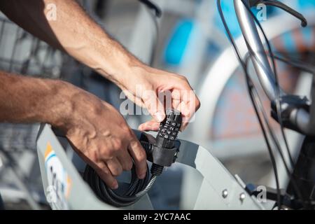 homme verrouillant bicyclette avec chaîne métallique à l'extérieur Banque D'Images