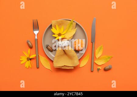 Belle table avec citrouille fraîche, glands, fleurs et feuilles d'automne sur fond orange Banque D'Images