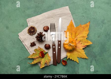 Couverts élégants avec des feuilles d'automne, des châtaignes, de la citrouille fraîche et de belles fleurs sur fond vert Banque D'Images