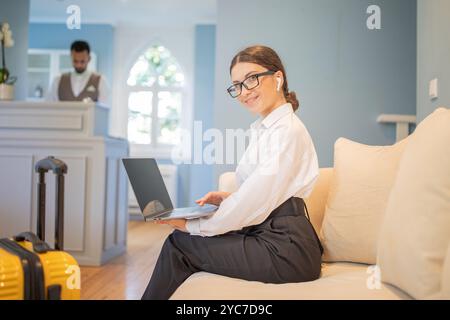 Femme d'affaires travaillant sur un ordinateur portable dans le hall de l'hôtel avec un membre du personnel amical Banque D'Images