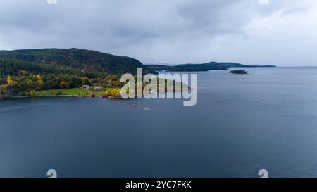 Vue aérienne d'un paysage côtier serein avec une mer calme, des collines verdoyantes et des îles dispersées. La scène est ornée de feuillage d'automne, sho Banque D'Images