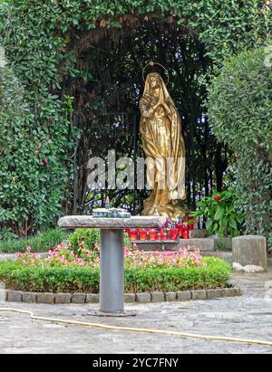 Opatija, Croatie - 08 octobre 2024 : statue religieuse dorée de la Vierge devant l'église Saint-Jacob à Opatija, Croatie avec verre rouge décoratif env Banque D'Images