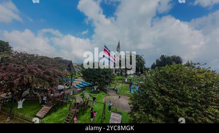 Belle vue aérienne FPV du drapeau du bicentenaire du Costa Rica dans le parc Coronado avec l'église gothique. Costa Rica Banque D'Images