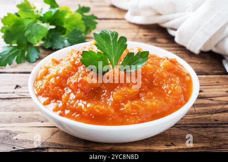 Caviar fait maison à partir de tomates courgettes et d'oignons dans une plaque en céramique sur un fond en bois. Conserves de production maison, conserves de légumes cuits en conserves Banque D'Images