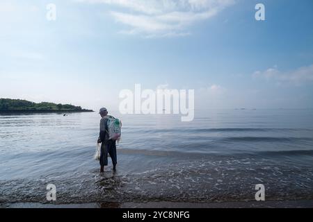 Un pêcheur observe la mer depuis le rivage avant de lancer son filet Banque D'Images