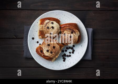 Kanelbulle petits pains à la cannelle avec crème au beurre sur une table en bois rustique. Pâtisseries fraîches faites maison Banque D'Images