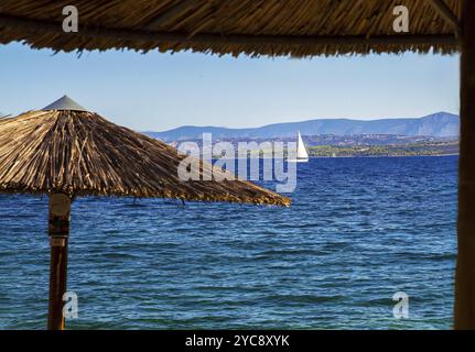 Voilier blanc se déplace sur le fond de la mer bleue (mer Méditerranée), auvents en paille du soleil en flou Banque D'Images