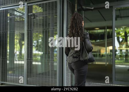 Vue arrière d'une femme d'affaires moderne latine entrant dans un bâtiment Banque D'Images