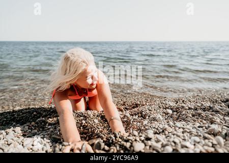 Femme blonde en bikini rose joue sur Pebble Beach Banque D'Images