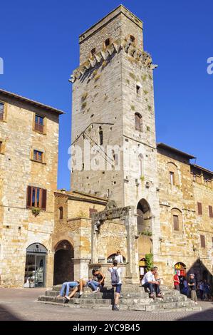 Touristes sur les marches de la citerne en face de Torre del Diavolo, l'une des 15 tours restantes, San Gimignano, Toscane, Italie, Europe Banque D'Images
