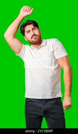 Un jeune homme dans un polo blanc danse énergiquement sur un fond vert éclatant Banque D'Images