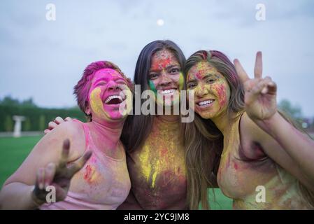 Trois jeunes amies indiennes couvertes de poudre colorée ou gulal célébrant holi festival de couleurs. Culture de l'inde. Banque D'Images