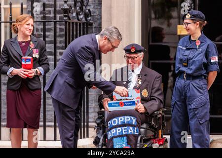 Downing Street, Londres, Royaume-Uni. 22 octobre 2024. Le premier ministre britannique Keir Starmer, rejoint par des membres des forces armées et des volontaires, achète un coquelicot devant la porte numéro 10 pour soutenir l'appel du coquelicot de la Royal British Legion 2024. Crédit : Amanda Rose/Alamy Live News Banque D'Images