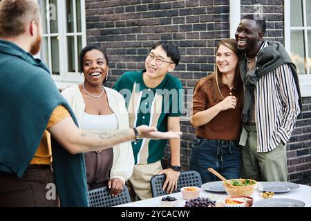 Groupe diversifié d'amis adultes joyeux souriants, prêts à savourer ensemble un repas en plein air Banque D'Images