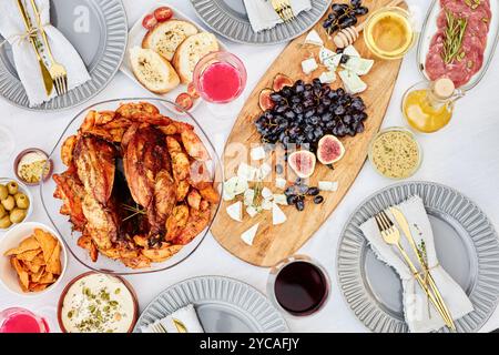 Vue de dessus image de fond de table de dîner festive avec délicieux plat de poulet rôti et panneau de charcuterie sur tissu blanc croustillant tourné avec flash Banque D'Images