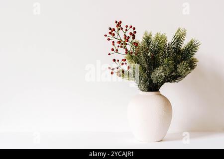 Composition de Noël minimaliste avec des branches de sapin dans un vase en céramique sur fond blanc. Vue de face. Copier l'espace Banque D'Images