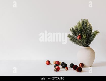 Composition de Noël minimaliste avec des branches de sapin dans un vase en céramique sur fond blanc. Vue de face. Copier l'espace Banque D'Images