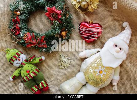 Père Noël portant une tenue blanche et dorée pour la célébration des vacances de Noël le 25 décembre avec bonhomme de neige, guirlande et décoration de boules de Noël. Banque D'Images