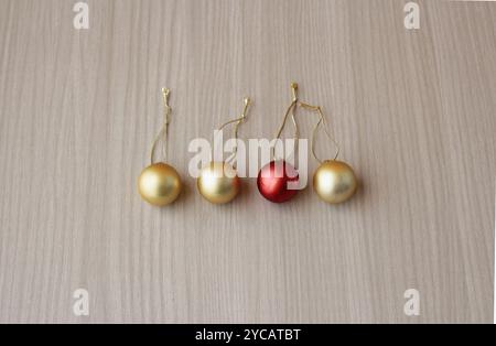 Quatre boules de noël, trois en couleur or et une en rouge. Boules, sphères, pendentifs pour la décoration de vacances de Noël sur fond de bois. Banque D'Images
