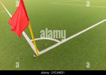 Drapeau de coin rouge debout sur un terrain de football vert avec des lignes blanches Banque D'Images