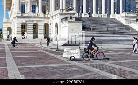 La police du Capitole suit un cycliste zélé anti-Trump tirant une bande-annonce « Trump Brand 666 (Hellbound, USA) » sur le terrain du Capitole américain, le 20 octobre 2024. Banque D'Images