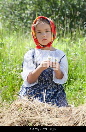 Portrait extérieur d'une petite fille avec des fleurs de camomille dans ses mains Banque D'Images