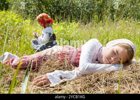 Petite fille dormant dans un champ tandis que sa petite sœur cueillait des fleurs Banque D'Images