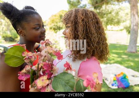 Cette image capture un moment tendre entre une afro-américaine et une femme LGBTQIA+ latino-américaine, entourée par la nature dans un cadre paisible de parc, Banque D'Images