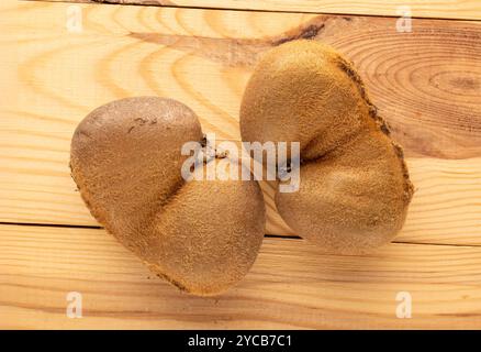 Deux kiwis juteux mûrs sur une table en bois, macro, vue de dessus. Banque D'Images