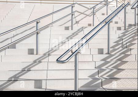 image abstraite de mains courantes et de marches en pierre blanche ou d'escaliers avec des ombres de mains courantes coulées sur les marches et les contremarches formant des motifs inhabituels. Banque D'Images