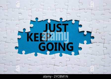 Symbole « continuez à aller ». Puzzle blanc avec des mots juste continuer. Beau fond bleu. Business and Just Keep Go concept. Copier l'espace. Banque D'Images