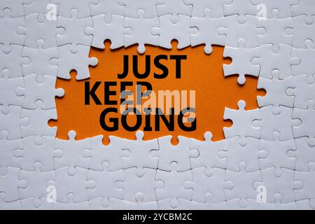 Symbole « continuez à aller ». Puzzle blanc avec des mots juste continuer. Beau fond orange. Business and Just Keep Go concept. Copier l'espace. Banque D'Images