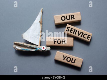 Notre service pour vous symbole. Blocs en bois avec des mots notre service pour vous. Beau fond gris avec bateau. Affaires et notre service pour vous concevez Banque D'Images