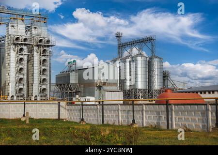 grand élévateur de grain avec plusieurs silos métalliques cylindriques, éléments structurels et un système complexe de tuyaux. Il se tient contre un ciel bleu, avec un f Banque D'Images