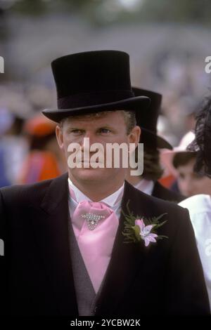 LGBT+ 1990s Royaume-Uni. Dandy gay à la mode portant un chapeau haut de gamme en soie noire traditionnelle et un costume noir du matin, partez avec une cravate rose et une fausse épingle de cravate de diamant, et un boutonnage rose. Il est en train de faire une apoint iof en rose. Il porte un diamant dans son lobe gauche de l'oreille. Ascot, Berkshire, Angleterre vers juin 1995 Angleterre HOMER SYKES Banque D'Images