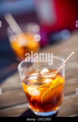 Un gros plan de deux verres remplis de cocktails rafraîchissants au vermouth sur une table de patio ensoleillée, soulignant les couleurs vives et l'ambiance accueillante. Banque D'Images