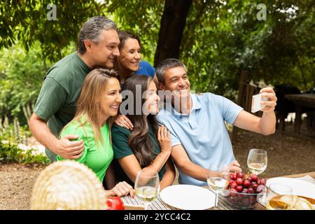 Réunion de famille en plein air en profitant d'un repas et en prenant un selfie ensemble Banque D'Images