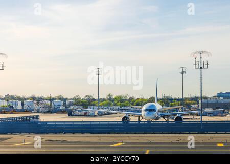 Taxis aériens sur la piste de l'aéroport international Newark Liberty (EWR) avec infrastructure aéroportuaire et conteneurs de fret en arrière-plan. New York. ÉTATS-UNIS Banque D'Images