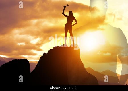 Vainqueur avec coupe trophée dans les montagnes au lever du soleil et silhouette de l'homme Banque D'Images