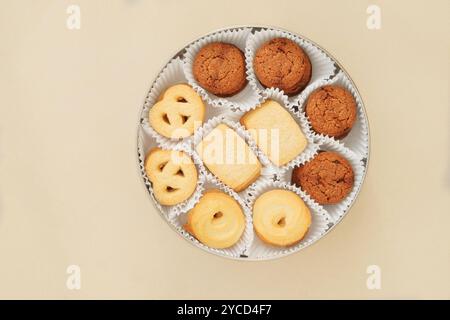 Biscuits sertis dans une boîte en métal. Dessert sucré pour les vacances sur fond beige. Variété de biscuit. Vue de dessus. Banque D'Images