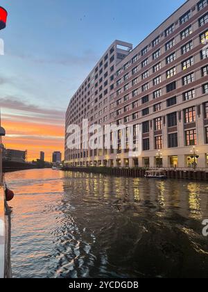 La grandeur Art déco se courbe le long des rives de Chicago, ses fenêtres illuminent la lueur cuivrée du coucher de soleil tandis que les eaux ondulantes reflètent le chef-d'œuvre urbain. Banque D'Images