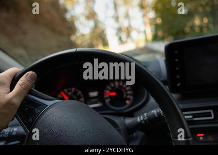 Main du conducteur sur le volant d'une voiture. Vue intérieure avec voiture en mouvement. Banque D'Images