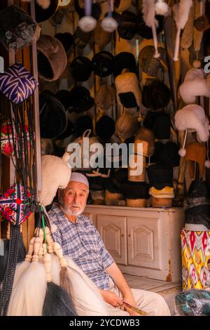 Kashgar, Chine - 17 JUILLET 2022 : homme ouïghour assis dans sa boutique traditionnelle de chapeaux ouïghours dans un marché local dans le vieux Kashgar Banque D'Images