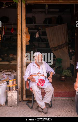 Kashgar, Chine - 17 JUILLET 2022 : homme ouïghour assis dans son magasin d'épices sur un marché local dans le vieux Kashgar Banque D'Images