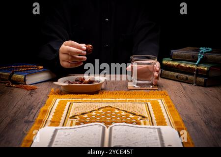 Beaucoup de palmiers dattiers sont sur des bols, des assiettes et des tasses d'eau, et le Coran est sur des tables en bois, pour attendre le temps de l'iftar, avec le concept de ramadan Banque D'Images